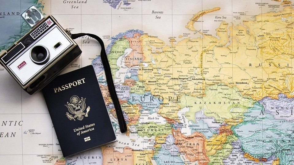 old camera and passport laying on a world map