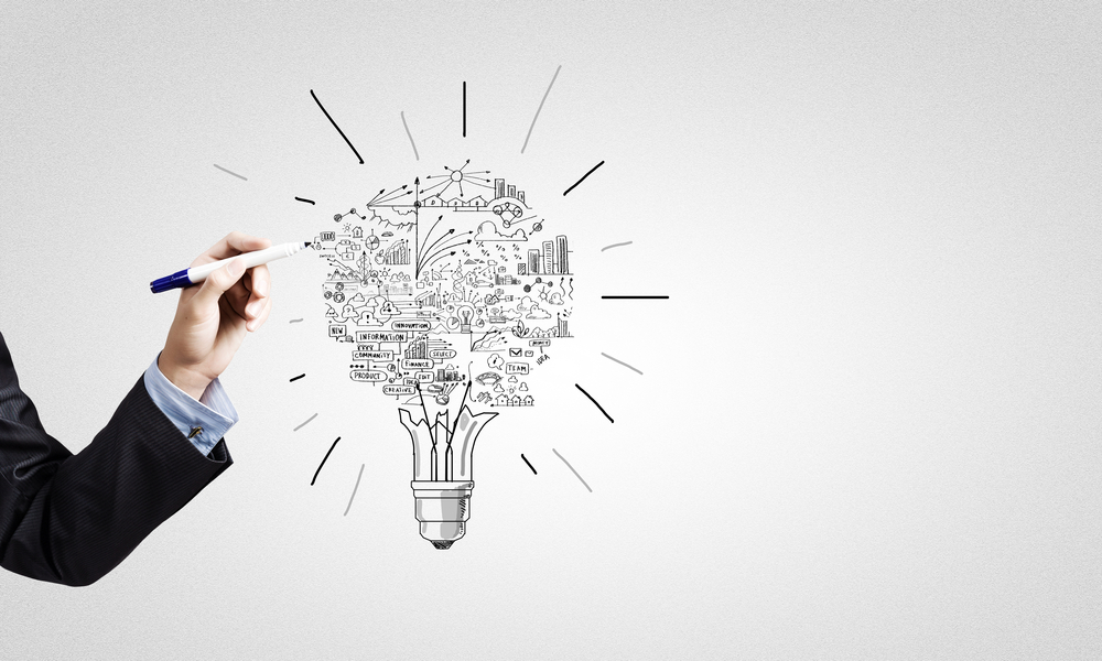 person drawing on a whiteboard, an image of a lightbulb made up of charts